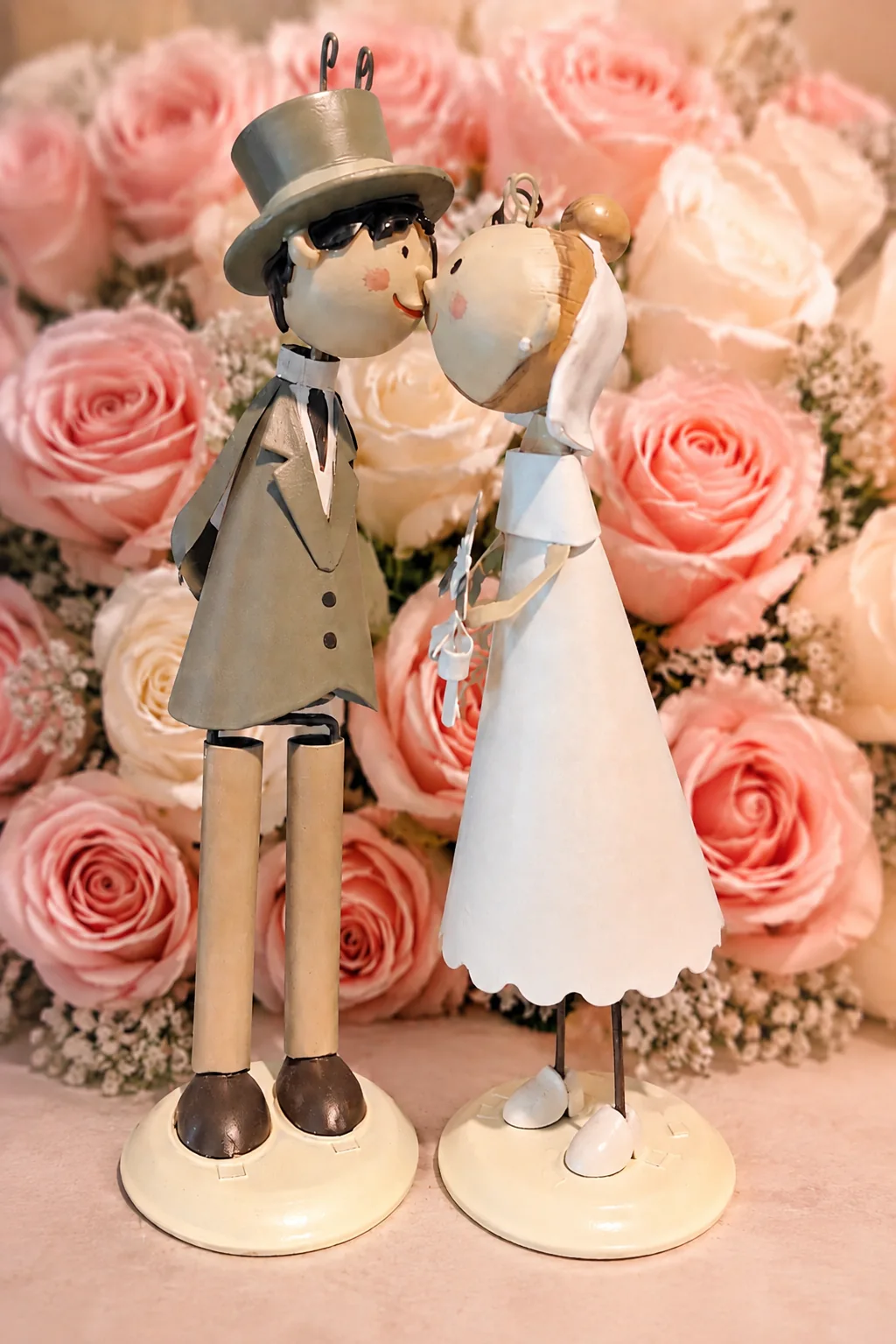 Brautpaarfiguren vor rosafarbenen Rosen