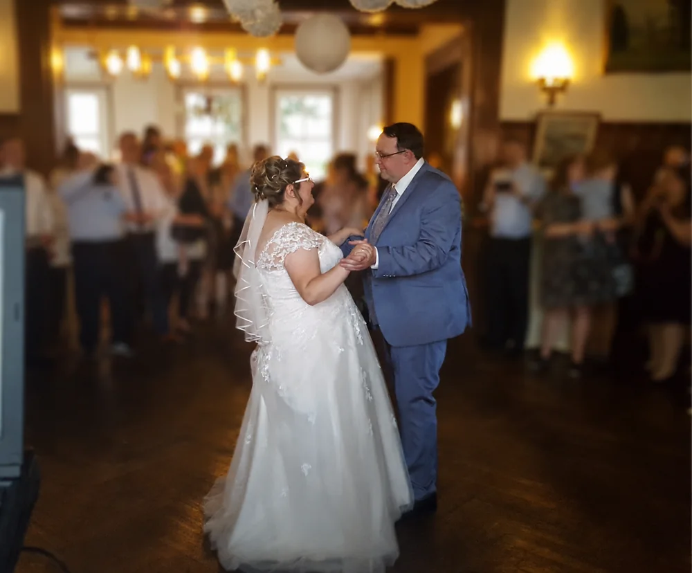 Brautpaar beim Hochzeitstanz mit Gästen im Hintergrund